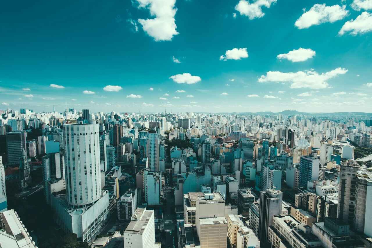 Vista aérea de São Paulo com muitos prédios sob céu azul com poucas nuvens.