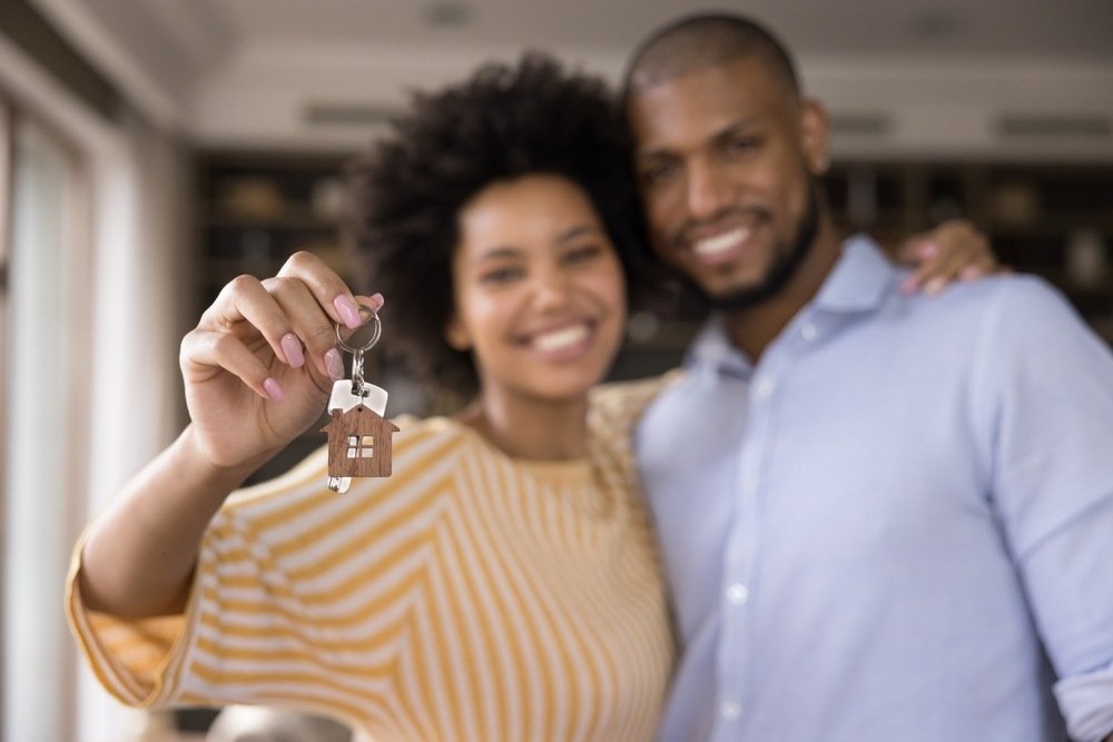 Casal com chave de apartamento na mão, após concluir o passo a passo de compra de imóvel