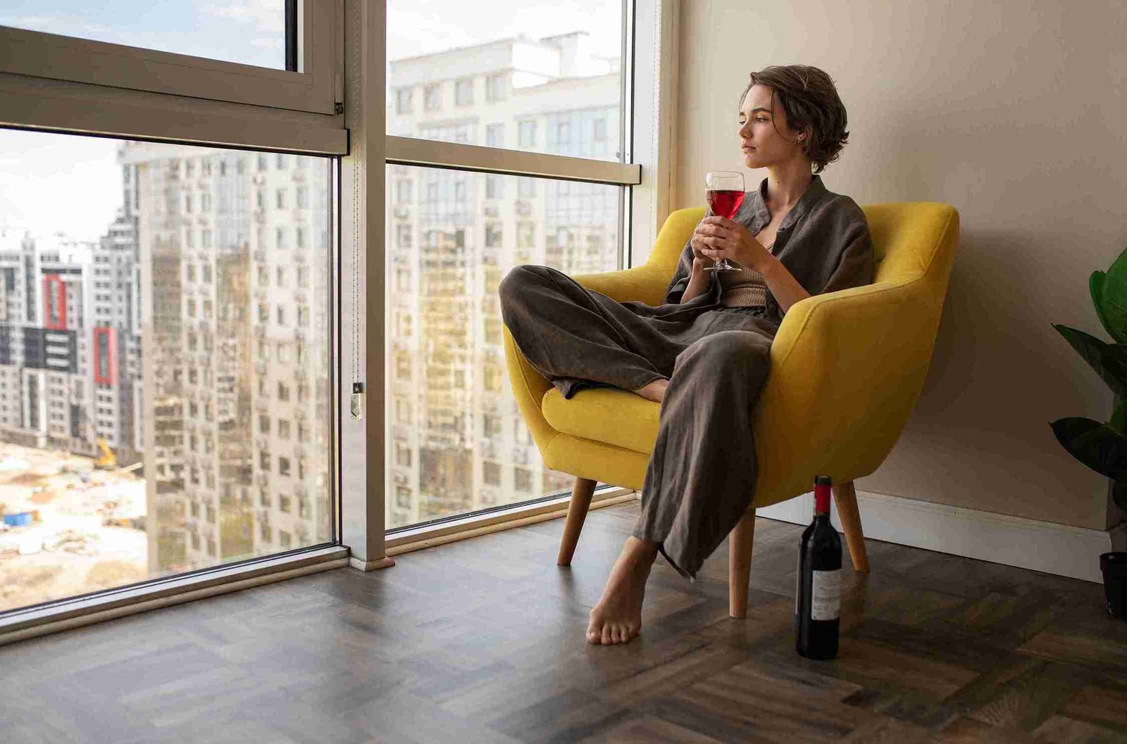 Moradora relaxando em apartamento com vista urbana, motivos para morar em Moema, São Paulo.